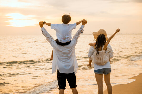 Happy family day. Parents carrying children on shoulders at the beach on sunset time, Father, Mother and kids playing together outdoors on summer beach, Family on holiday summer vacation travel