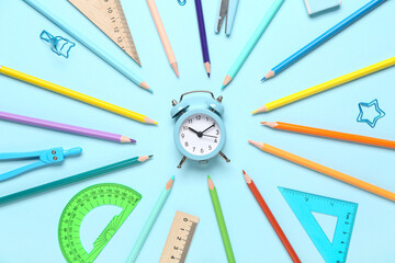 Frame made of alarm clock and school stationery on blue background
