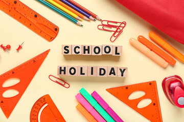 Frame made of different school stationery and wooden cubes with text SCHOOL HOLIDAY on beige background