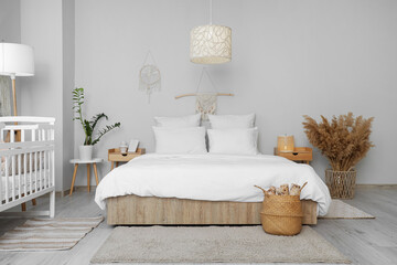 Interior of room with bed, baby crib and tables