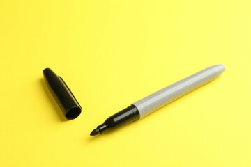 One black marker on yellow background. Space for text
