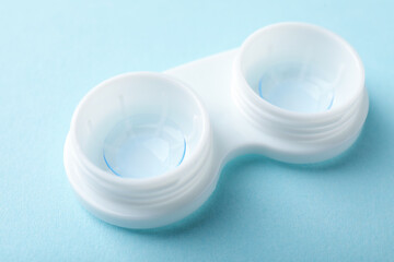 Contact lens in case on light blue background, closeup
