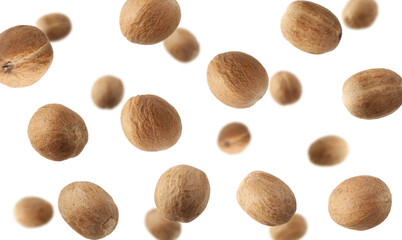 Aromatic nutmeg seeds falling on white background
