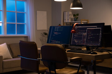 Programmer's desk with computer monitors and glowing lamps in dark office at night
