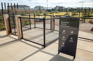 A secure, fenced entrance to an off-leash dog park within a suburban recreation reserve in...