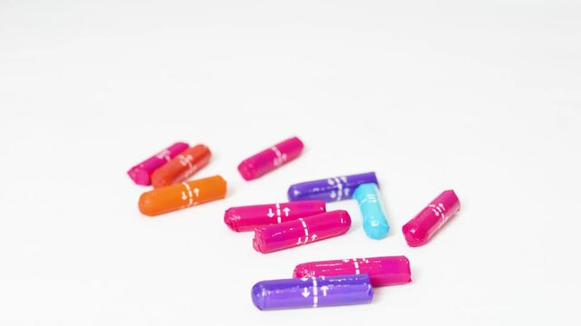 Feminine hygiene tampons arranged in colorful pattern, spreading dynamically across clean white surface, representing menstrual health and personal care wellness