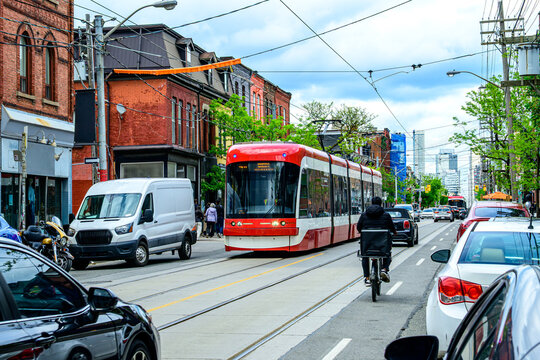 public transport: modern tram car and food delivery bike courrier on city street shot in the queen west area of toronto on a sunny spring day - Powered by Adobe