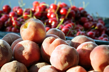 Erotic still life. Peaches against a background of cherries. Juicy, textured peaches are piled against a backdrop of ripe cherries.
