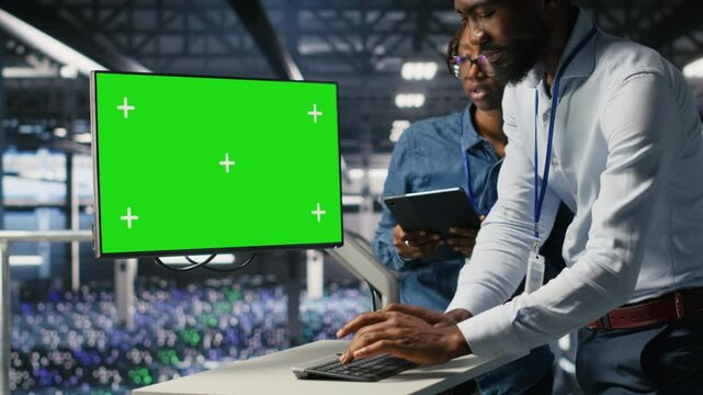 Server room coworkers doing brainstorming, using chroma key device to review diagnostics. Employees doing maintenance tasks in data center, looking at isolated screen monitor, camera B