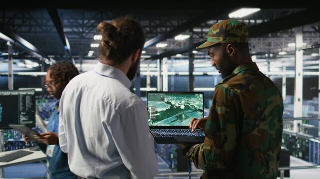 Drone operators in military data center supervising autonomous flight systems through laptop interface. Teamworking army IT experts doing live drone tracking using notebook, camera A