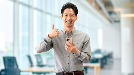 スマートフォンを持っていいね！のポーズをする男性