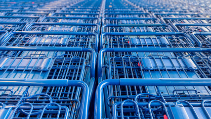 Many blue shopping carts for customers are stacked and arranged in rows outside the super market. © SNEHIT PHOTO