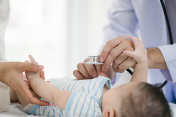 A male doctor meticulously examines a three-month-old infant, conducting a thorough health checkup...