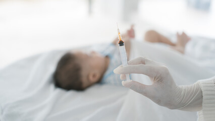 Asian loving mother comforts her three-month-old, as a male doctor administers essential childhood...