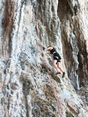 climber on a rock Female athlete top rope rock climbing at Railay Beach, Ao Nang, Krabi Province,...