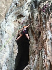 young woman climbing a tree Female athlete top rope rock climbing at Railay Beach, Ao Nang, Krabi...