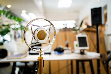 A microphone is sitting on a desk in front of a computer. The microphone is surrounded by a...