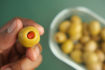 Holding a green olive stuffed with red pepper