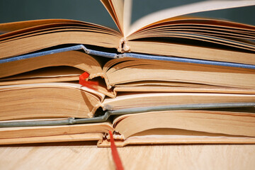 Stacked open books with colorful bookmarks on a wooden table
