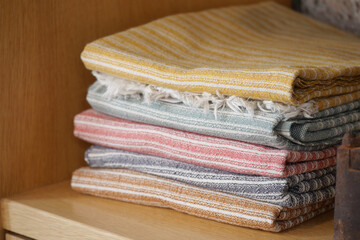 Colorful woven textiles stacked on a wooden shelf