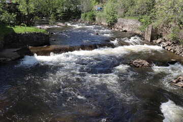 River in the forest. Summer calendar and rapids in the nature with trees. Drinking water of a city. The current of the water and stones with waterfalls. The St-Charles river in Quebec and in spring.