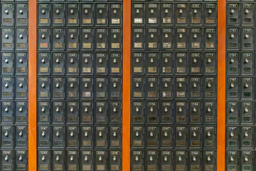 Photo of rows of numbered brown metal college, university campus mail boxes with a small window and...
