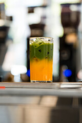 Iced matcha latte separated layers, matcha green tea with fresh orange juice, summer drink