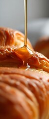 spoon is dripping honey onto a pastry