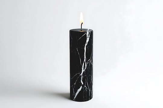A black marble candle with a lit wick on a white background casts a soft shadow below it