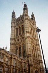 Naklejka premium Historic Gothic architecture of the Palace of Westminster in London England, captured on film with vintage tones and classic British charm under a soft sky.