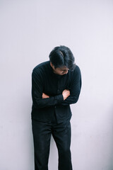Brooding man in black, arms crossed, expressing introspection