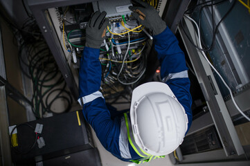 Server expert repair technicians are checking the integrity of server cabinet cable connections to...