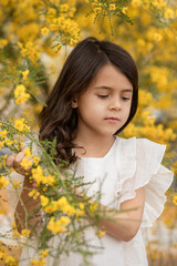 Spring portrait of little girl holding blooming yellow flowers, childhood memories and happy kids concept