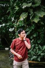 Toothache suffering man in tropical garden background with hand on face