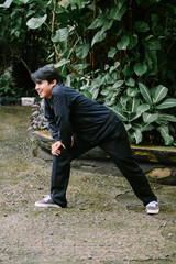 Smiling young man stretching outdoors, enjoying natural green setting
