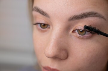 Obraz premium Young Woman Applying Mascara to Enhance Eyelashes. 