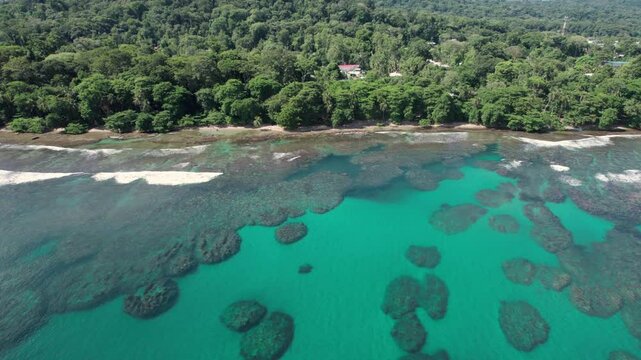 Aerial zoom-in with pan right over Cocles beach, showing clear waters and lush vegetation.