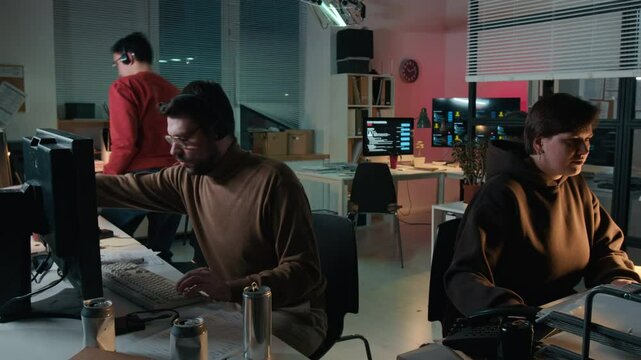 Wide time lapse surveillance camera shot of multiethnic scam call center employees working together in office, typing on computers, talking on phone to victims, discussing extortion tactics
