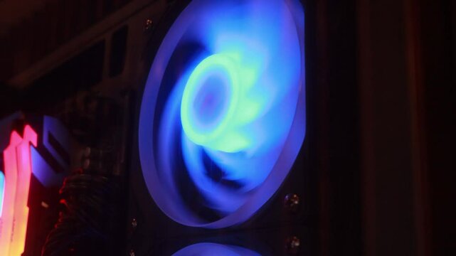 A bright cooling fan spins rapidly inside a computer case, illuminating the surrounding area with a warm glow as the gaming session heats up and enhances performance on a relaxing night
