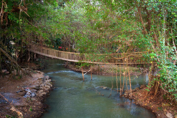 Suspended bridge over tranquil river in Buon Don district, Dak Lak province, Vietnam surrounded by lush greenery