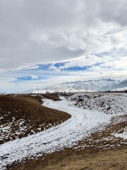 Snow covered mountains in Kyrgyzstan under cloudy winter sky peaceful rural landscape
