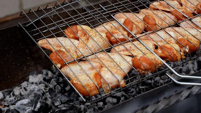 BBQ picnic time Roasted chicken legs and wings on grill. Grilling meat on outdoor grill grid tasty barbeque chicken steak with smoke flames juicy meat in the backyard in summer