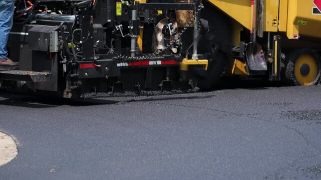 Asphalt paving machine laying fresh blacktop on the road. road roller pressing down freshly laid asphalt.