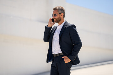 Office worker talking on cellphone outside. Businessman talk on mobile phone. Businessman having...