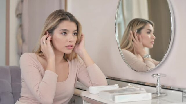 Young woman touching her face while looking in the mirror, calm skincare and self-care moment at home, natural beauty, wellness and personal reflection