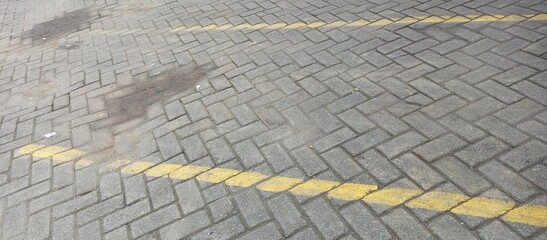 Fototapeta premium Gray Paving Stones with Yellow Parking Lot Lines