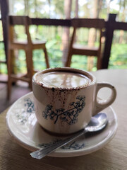 A cup of hot black coffee, served in a cafe with a nature theme.
