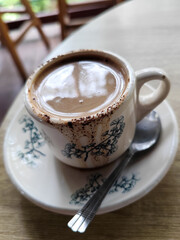 A cup of hot black coffee, served in a cafe with a nature theme.