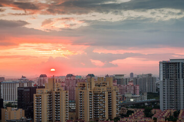 Fototapeta premium Colorful sunset in Gurgaon urban skyline in monsoon.Gurugram,Haryana,India cityscape with modern architecture,commercial and luxury residential apartment buildings.Aerial view of Delhi NCR.