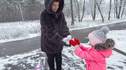 Grandmother with grandchildren in warm clothes playing outdoors in winter park, enjoying snowy...